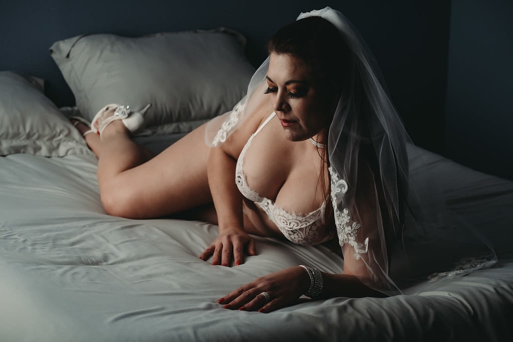 Women laying on bed wearing white lingerie, heels and veil. Photo by Embodied Art Boudoir. Classic boudoir photography, classic photography, classic boudoir, classy boudoir, classy photography, sensual photography, sensual boudoir, colorado boudoir, denver boudoir, boulder boudoir, colorado springs boudoir, boudoir ideas, boudoir poses, boudoir inspiration, photography inspiration, romantic boudoir, bridal boudoir
