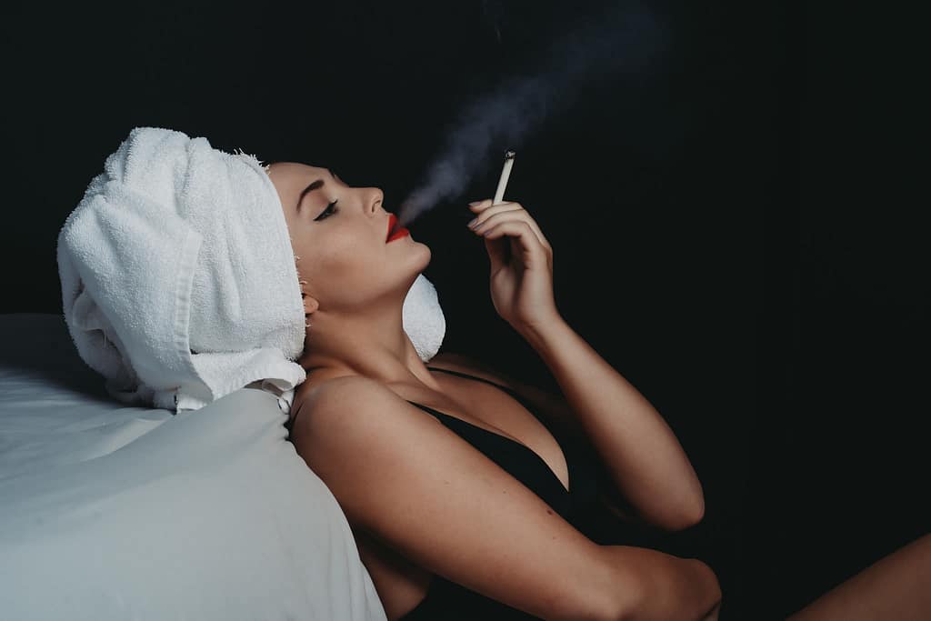 Woman leaning on bed smoking a cigarette with a towel on her head wearing a black bralette. Photo by Embodied Art Boudoir. Modest boudoir photography, Modest Fashion, Modest Woman, Fashion Trends, Shy, classy photography, classic boudoir, classy boudoir, feminine photography, colorado boudoir, denver boudoir, boulder boudoir, colorado springs boudoir, boudoir ideas, boudoir poses, boudoir inspiration, photography inspiration, boudoir session, boudoir photos