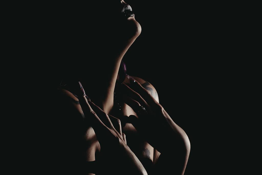 Silhouette of woman holding chest nude, wearing dark lipstick. Photo by Embodied Art Boudoir. Dark and moody, black and white photography, intense images, high intensity, memorable, sensual photography, sensual boudoir, colorado boudoir, denver boudoir, boulder boudoir, colorado springs boudoir, boudoir ideas, boudoir poses, boudoir inspiration, photography inspiration, romantic boudoir, bridal boudoir