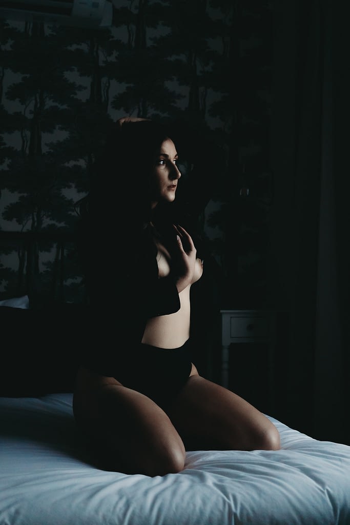Women sitting in the dark on the bed with a blazer on but nothing underneath. Photo by Embodied Art Boudoir. Photography Bachelorette Party, Denver boudoir photographer, golden boudoir photographer, colorado boudoir photographer, Boudoir photoshoot, boudoir photography, boudoir inspiration, boudoir photography ideas, sensual photography, self love, bachelorette party, bridal boudoir, dark and moody boudoir, boudoir parties, colorado boudoir photography