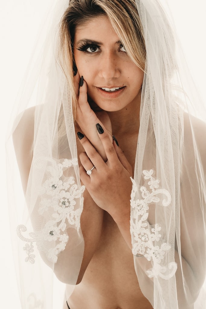 Nude woman wearing only a bridal veil with lace details smiling up at the camera. Photo by Embodied Art Boudoir. Wedding gift, wedding present, fiance gift, romantic gift, boudoir photography, boudoir album, boudoir photo album, newlywed, engaged, engagement present, engagement gift, boudoir party, bachelorette, bachelorette party, unique gift idea, husband gift, wife gift, denver boudoir photographer, colorado boudoir, Boudoir Photo Album, white lingerie, bridal lingerie, bridal boudoir