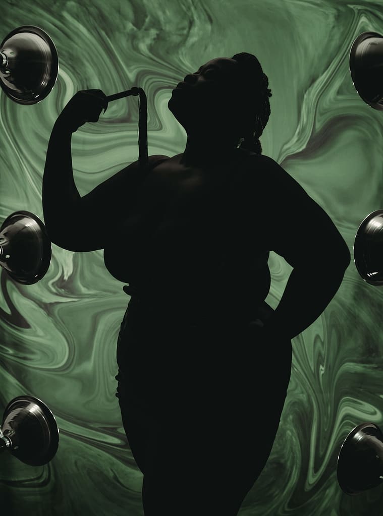 Silhouette of woman standing with head back holding onto a whip with psychedelic green background. Photo by Embodied Art Boudoir. Dark and moody, black and white photography, intense images, high intensity, memorable, sensual photography, sensual boudoir, colorado boudoir, denver boudoir, boulder boudoir, colorado springs boudoir, boudoir ideas, boudoir poses, boudoir inspiration, photography inspiration, romantic boudoir, bridal boudoir