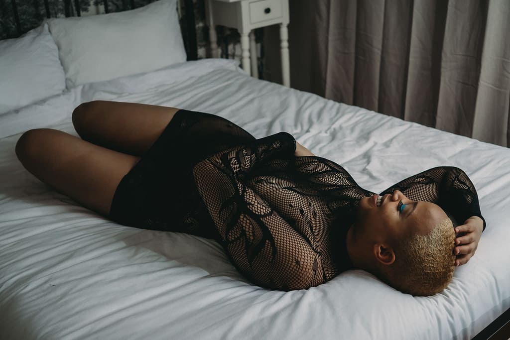 Women wearing a long sleeves bodysuit lounging on the bed looking happy. Photo by Embodied Art Boudoir. Modest photography, modest boudoir, modest photoshoot outfit, modest outfit ideas, boudoir photography, boudoir photoshoot, boudoir session, covered up, Colorado photographer, Denver boudoir photographer, Colorado boudoir photography, studio photography, body positivity, body positive photography, you don't need to be naked for a boudoir photoshoot, naked, nude
