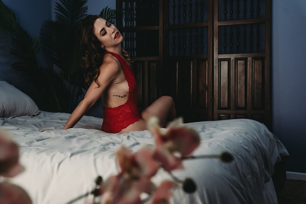 Woman sitting on the edge of the bed wearing a red lacy body suit with open back. Photo by Embodied Art Boudoir. A healthy relationship with food, mindful eating, love your food, non-judgemental, food freedom, anti-diet, self-compassion, mindfulness, self-love, dietary needs, slow down, appreciate food, appreciate life,  colorado boudoir, denver boudoir, boulder boudoir, colorado springs boudoir, boudoir ideas, boudoir poses, boudoir inspiration 