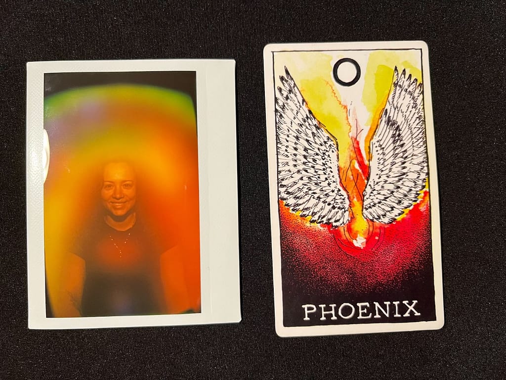 A polaroid image of woman smiling with varying colors around beside a graphic card of a Phonenix. Aura photography, aura photo, aura portrait, denver, colorado, kirlian photography, kirlian, boudoir photographer, friends aura photo, partner aura photo, couples aura photo, couples aura