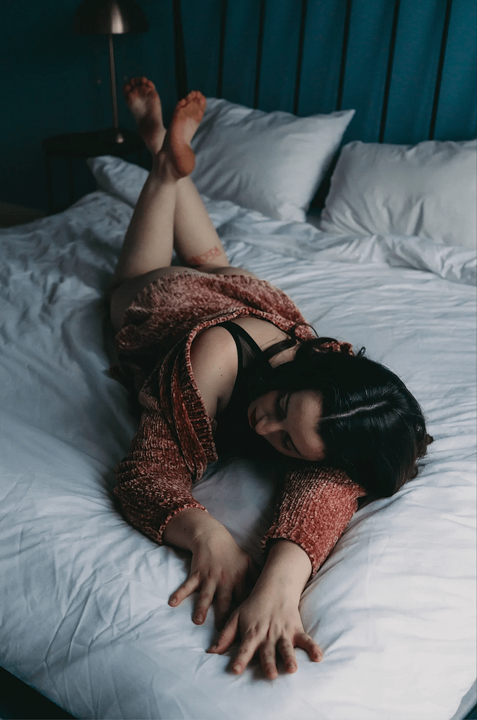 Woman lying on stomach wearing a orange sweater. Photo by Embodied Art Boudoir, cozy, cozy boudoir, cozy vibes, cozy outfits, cozy and comfortable, cozy boudoir photography, cozy inspiration, keep it cozy, boudoir outfit, boudoir outfit inspiration, what to wear to boudoir, colorado boudoir, denver boudoir, boulder boudoir, colorado springs boudoir, boudoir ideas, boudoir poses, boudoir inspiration, photography inspiration