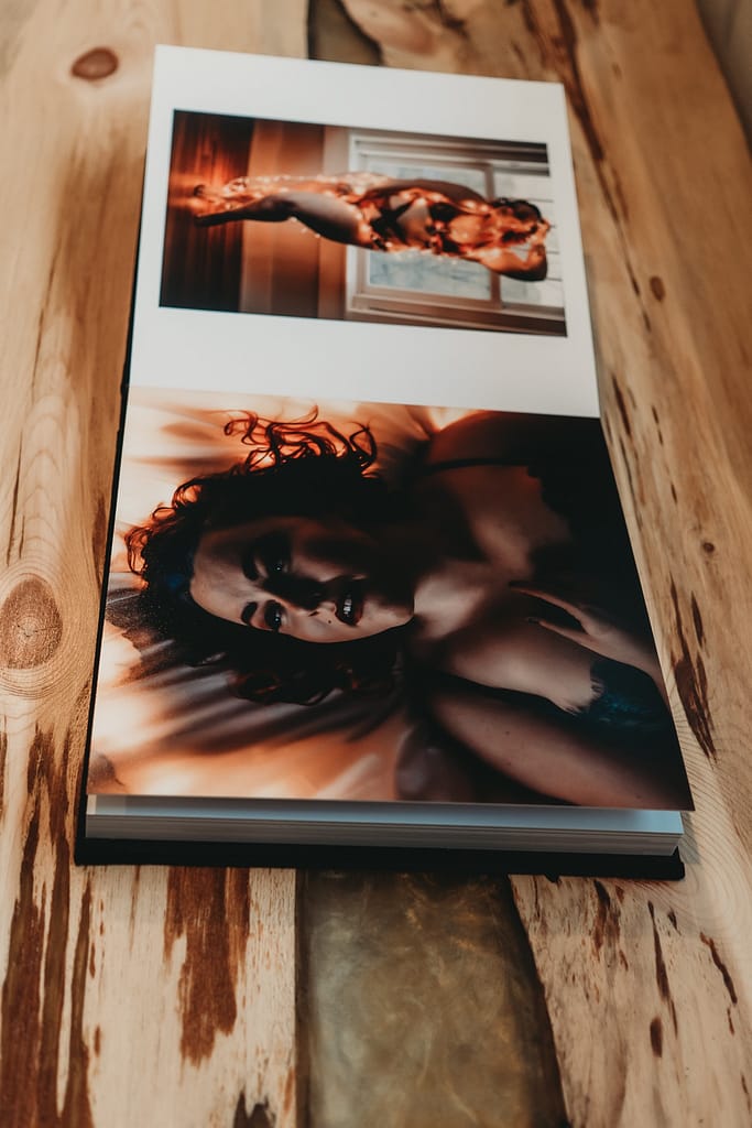 Boudoir photo album on a wood tabletop showing two stunning portraits of a plus size women with red hair. Photo by Embodied Art Boudoir. Boudoir photography, boudoir photoshoot, photoshoot, photo book, photo album, velvet cover, velvet album, boudoir album, black album, professional album, professional printer, wall art, prints, folio box, folio, collection, nude art, photography, golden boudoir, colorado boudoir photographer, denver boudoir photographer
