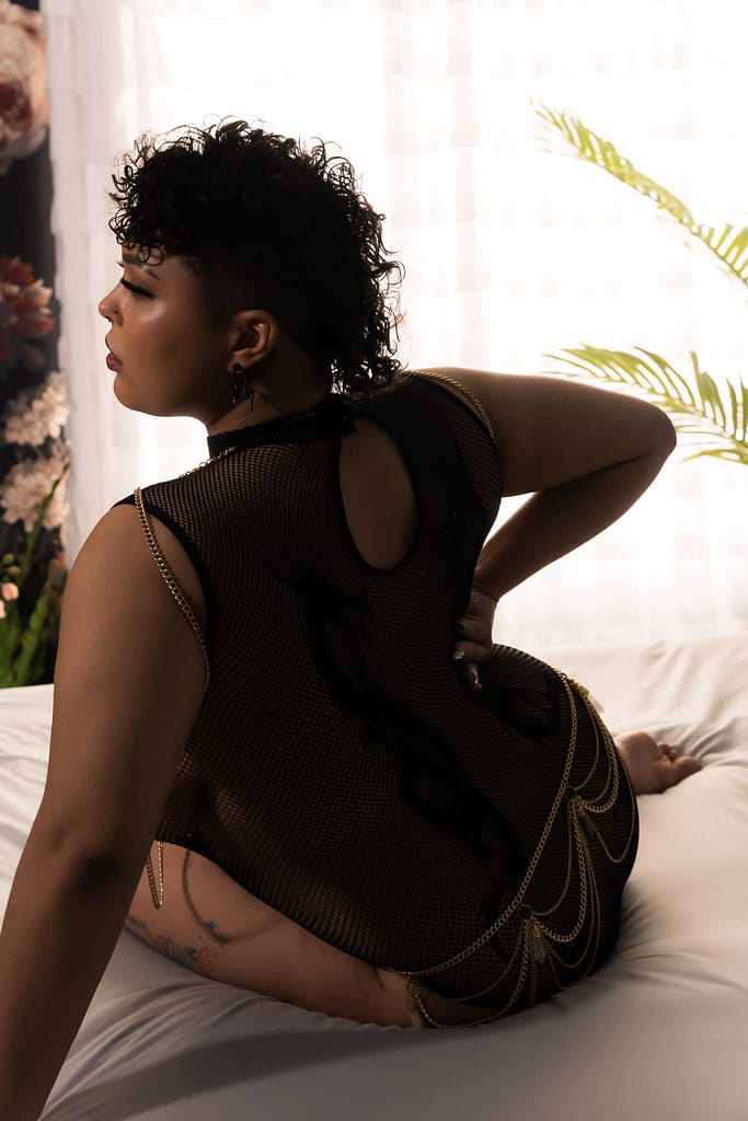 Woman sitting on bed, facing away from camera looking to the side wearing a black jumpsuit with gold body chains. Photo by Embodied Art Boudoir. Modest boudoir photography, Modest Fashion, Modest Woman, Fashion Trends, Shy, classy photography, classic boudoir, classy boudoir, feminine photography, colorado boudoir, denver boudoir, boulder boudoir, colorado springs boudoir, boudoir ideas, boudoir poses, boudoir inspiration, photography inspiration, boudoir session, boudoir photos