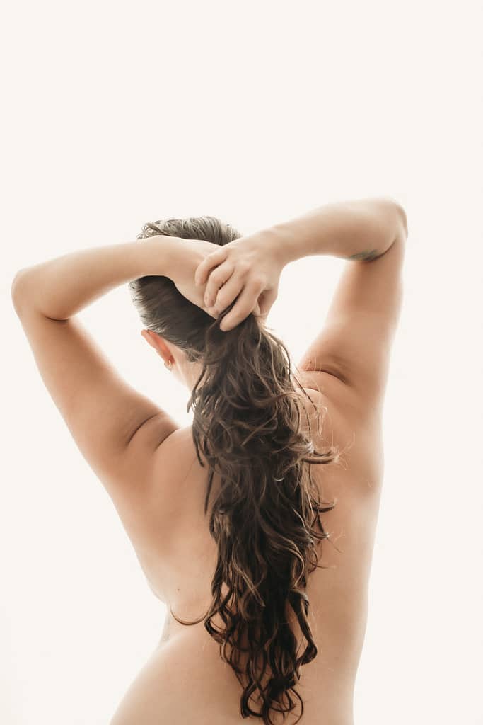 Brunette woman's holding hair back into pony tail, wearing no clothing.  Photo by Embodied Art Boudoir. Books to read, personal growth, personal transformation,  self care, support, novels, great reads, feminine photography, colorado boudoir, denver boudoir, boulder boudoir, colorado springs boudoir, boudoir ideas, boudoir poses, boudoir inspiration, photography inspiration, boudoir session, boudoir photos