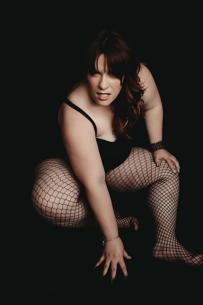 Woman crouching looking fiercely at the camera wearing a black body suit and black fishnet stockings. Photo by Embodied Art Boudoir. Growth, personal growth, self-love, caring for the mind, journal, journaling, journal prompts, write, writer, mindfulness, self reflection, inspiration, self-care, sensual photography, sensual boudoir, colorado boudoir, Denver boudoir, boulder boudoir, colorado springs boudoir, boudoir ideas, boudoir poses, boudoir inspiration, photography inspiration