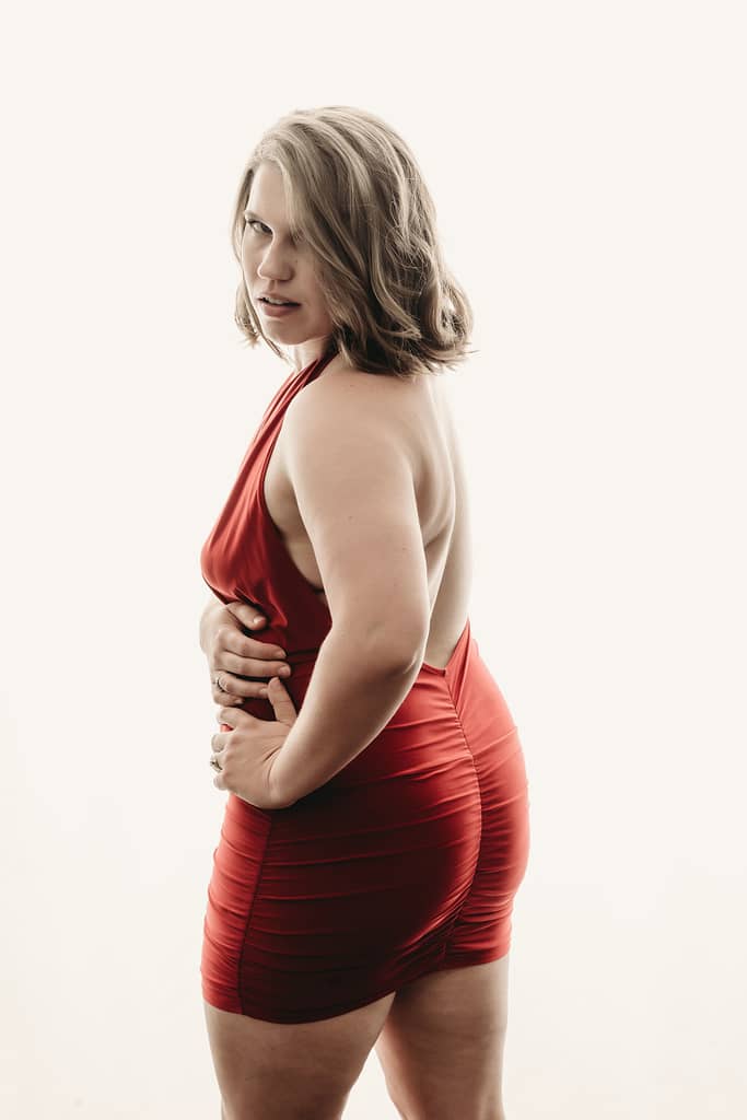 Blonde woman wearing a low baack red tight dress.  Photo by Embodied Art Boudoir. high key photography, high key, bright photohraphy, sensual photography, sensual boudoir, colorado boudoir, denver boudoir, boulder boudoir, colorado springs boudoir, boudoir ideas, boudoir poses, boudoir inspiration, photography inspiration, romantic boudoir, bridal boudoir, female empowerment, female photographer 