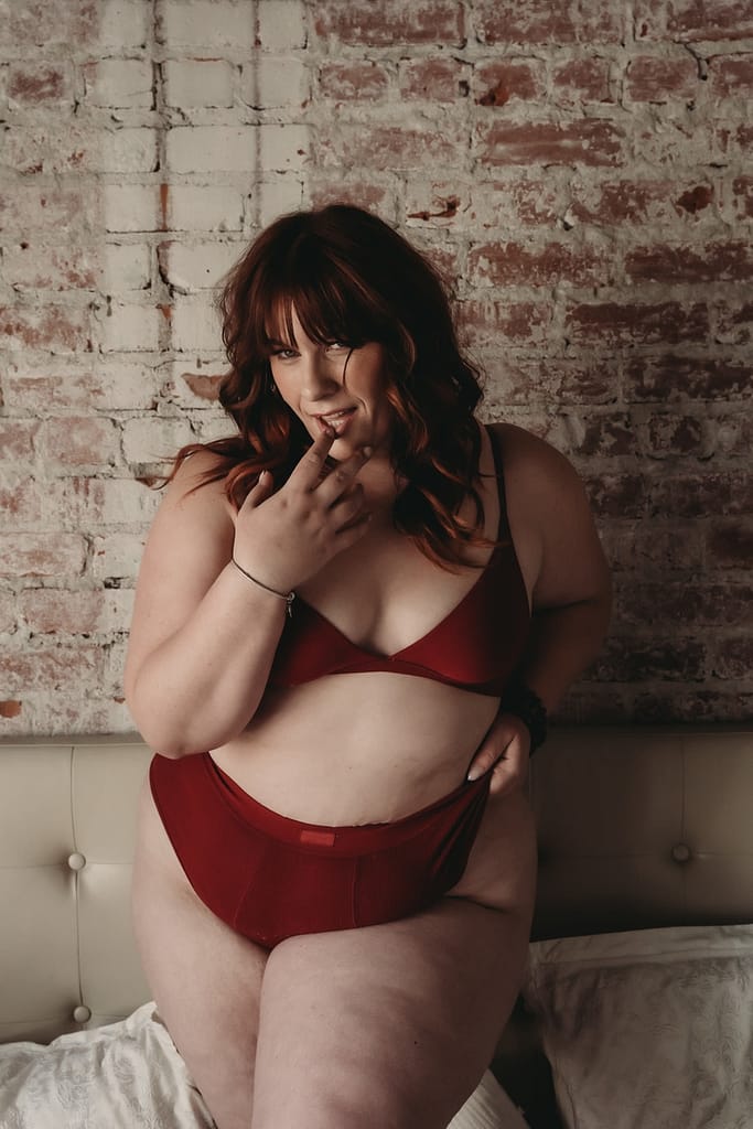 Woman standing in front of brick wall, wearing a matching red bralette and panties. Photo by Embodied Art Boudoir. Boudoir images, powerful women, sexy at any weight, body confidence, body image, self love, self confidence, changes, confident women, self care practices, challenge yourself, boudoir inspiration, boudoir images, colorado boudoir, denver boudoir, boulder boudoir, colorado springs boudoir, female photographer, body positive studio

