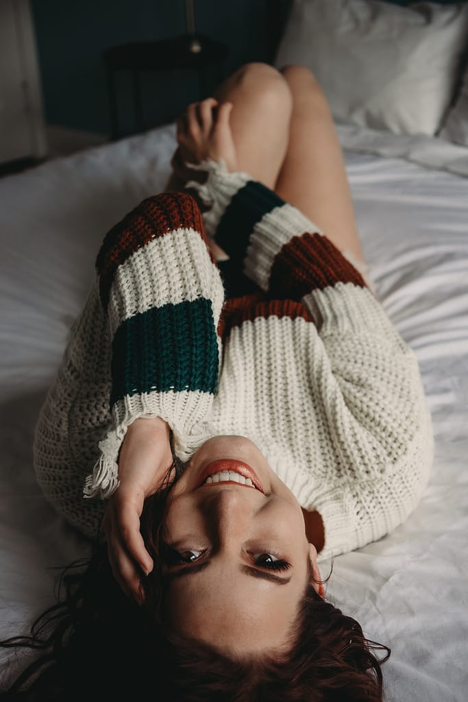 Woman lying on her back wearing a striped white sweater. Photo by Embodied Art Boudoir, cozy, cozy boudoir, cozy vibes, cozy outfits, cozy and comfortable, cozy boudoir photography, cozy inspiration, keep it cozy, boudoir outfit, boudoir outfit inspiration, what to wear to boudoir, colorado boudoir, denver boudoir, boulder boudoir, colorado springs boudoir, boudoir ideas, boudoir poses, boudoir inspiration, photography inspiration