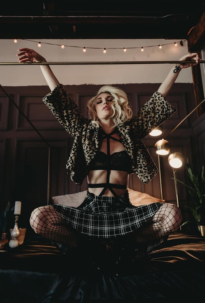 Blonde woman crouching near bed wearing a tartan skirt, black bra, and leopard print jacket. Photo by Embodied Art Boudoir. Growth, confidence, self-confidence, boundaries, boundary, boundary setting, saying no, self-worth, female empowerment, self-love, self-care practice, healthy relationships, emotional boundaries, physical boundaries, boundaries with family, boundaries at the holidays, boudoir, boudoir photo shoot, boudoir inspiration, colorado boudoir, denver boudoir, boulder boudoir, colorado springs boudoir